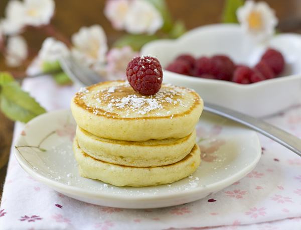 orange mochi pancakes with powdered sugar and fresh raspberries