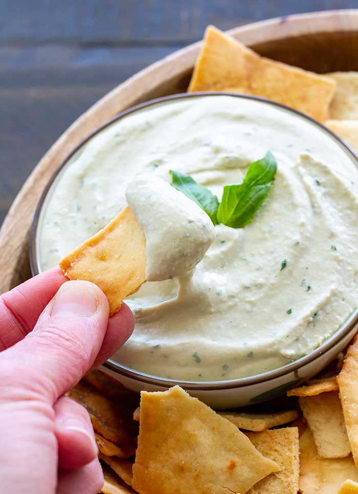 Bowl of lemon basil white bean dip with pita chips